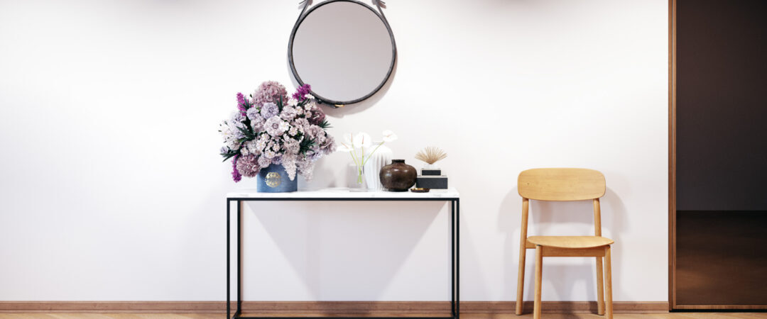 Une entrée joliment décorée avec une console au plateau en marvre surmontée d'un large miroir rond.