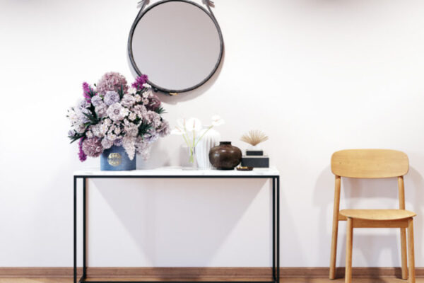 Une entrée joliment décorée avec une console au plateau en marvre surmontée d'un large miroir rond.