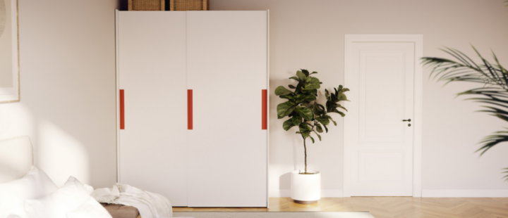 Un dressing blanc avec des poignées rouges installé dans une chambre à coucher.