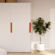 Un dressing blanc avec des poignées rouges installé dans une chambre à coucher.