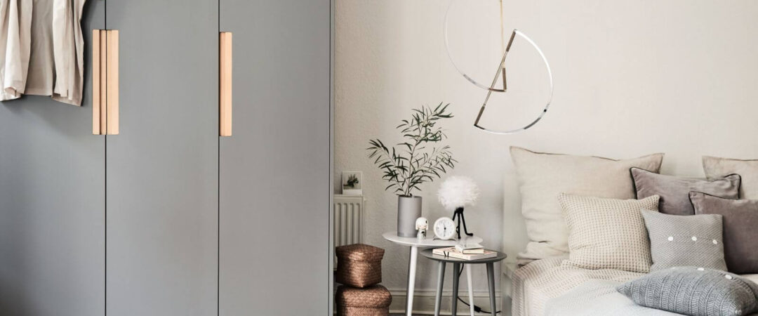 Une petite chambre décorée et aménagée avec deux tables de chevet et un dressing gris et étroit.