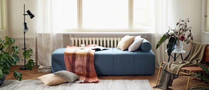 Un daybed bleu décoré avec des coussins et un plaid.