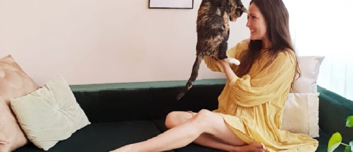 Une jeune femme assise sur un canapé avec un chat.