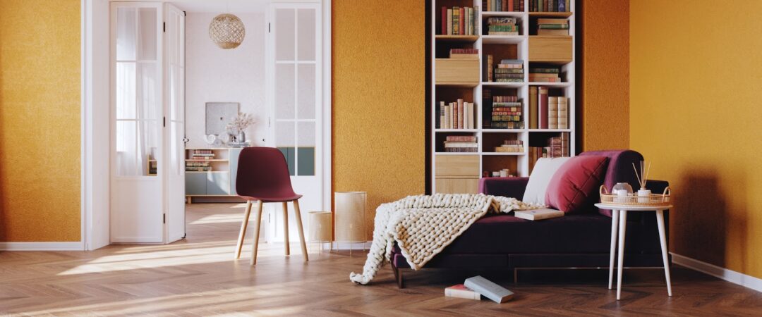 Un coin lecture chaleureux avec une méridienne marron, un plaid en tricot, un large coussin et une bibliothèque.