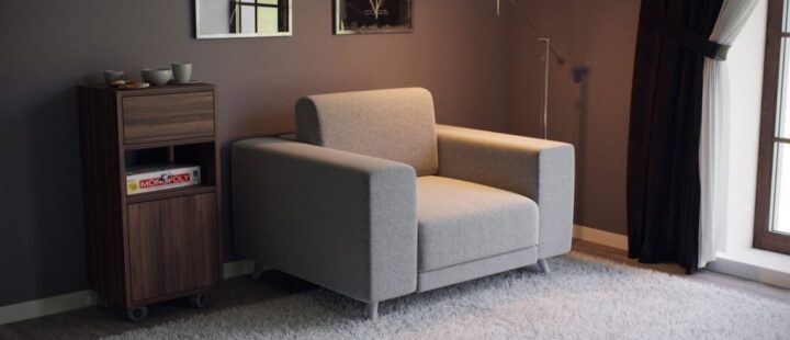 Un fauteuil gris avec de larges accoudoirs.