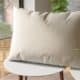 Un coussin beige posé sur une petite table blanche